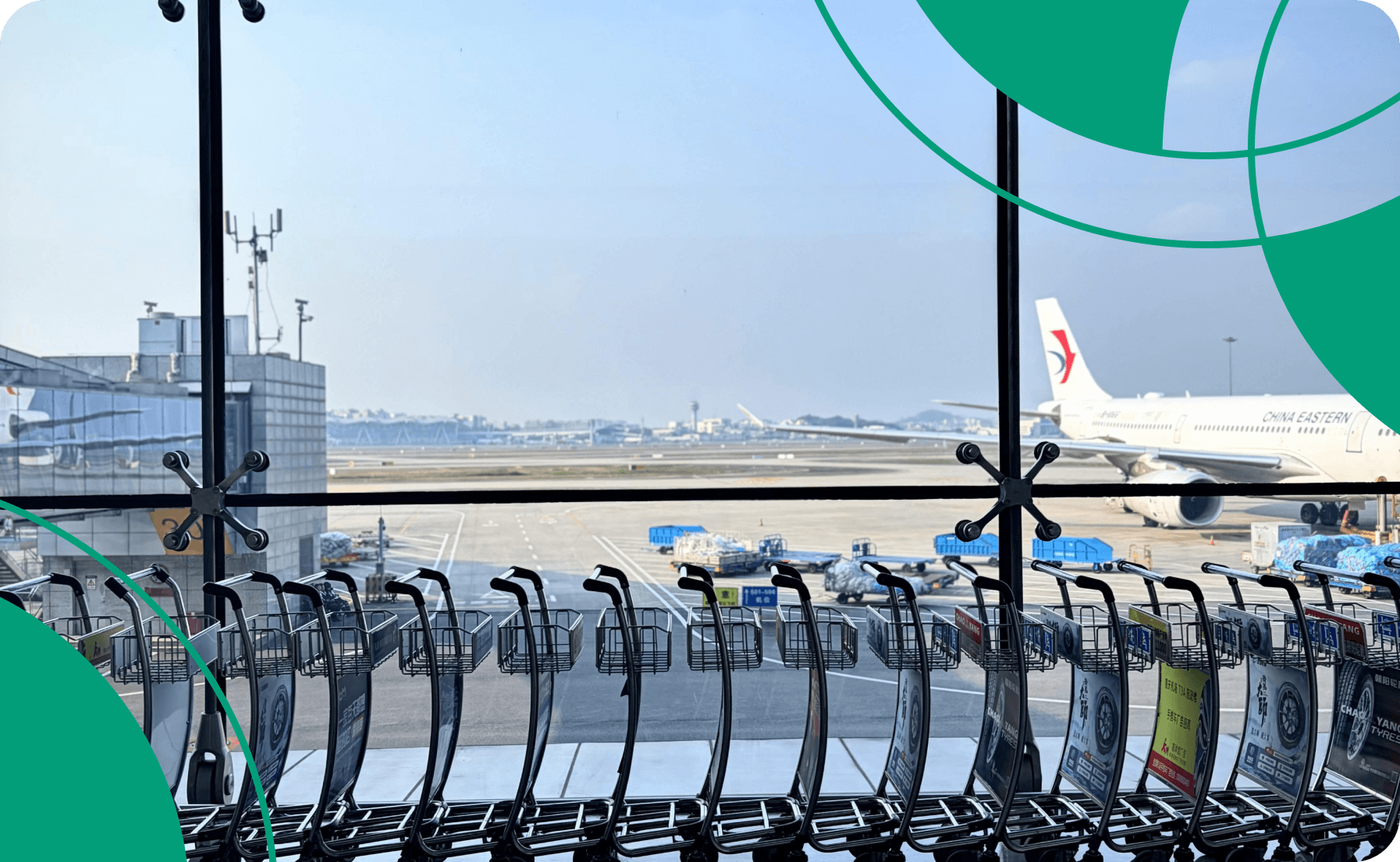 Airport terminal view through glass with luggage carts lined up on the tarmac