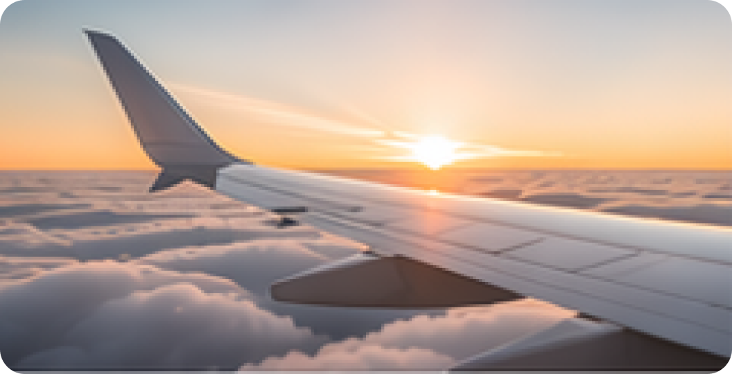 Airplane wing above clouds at sunrise